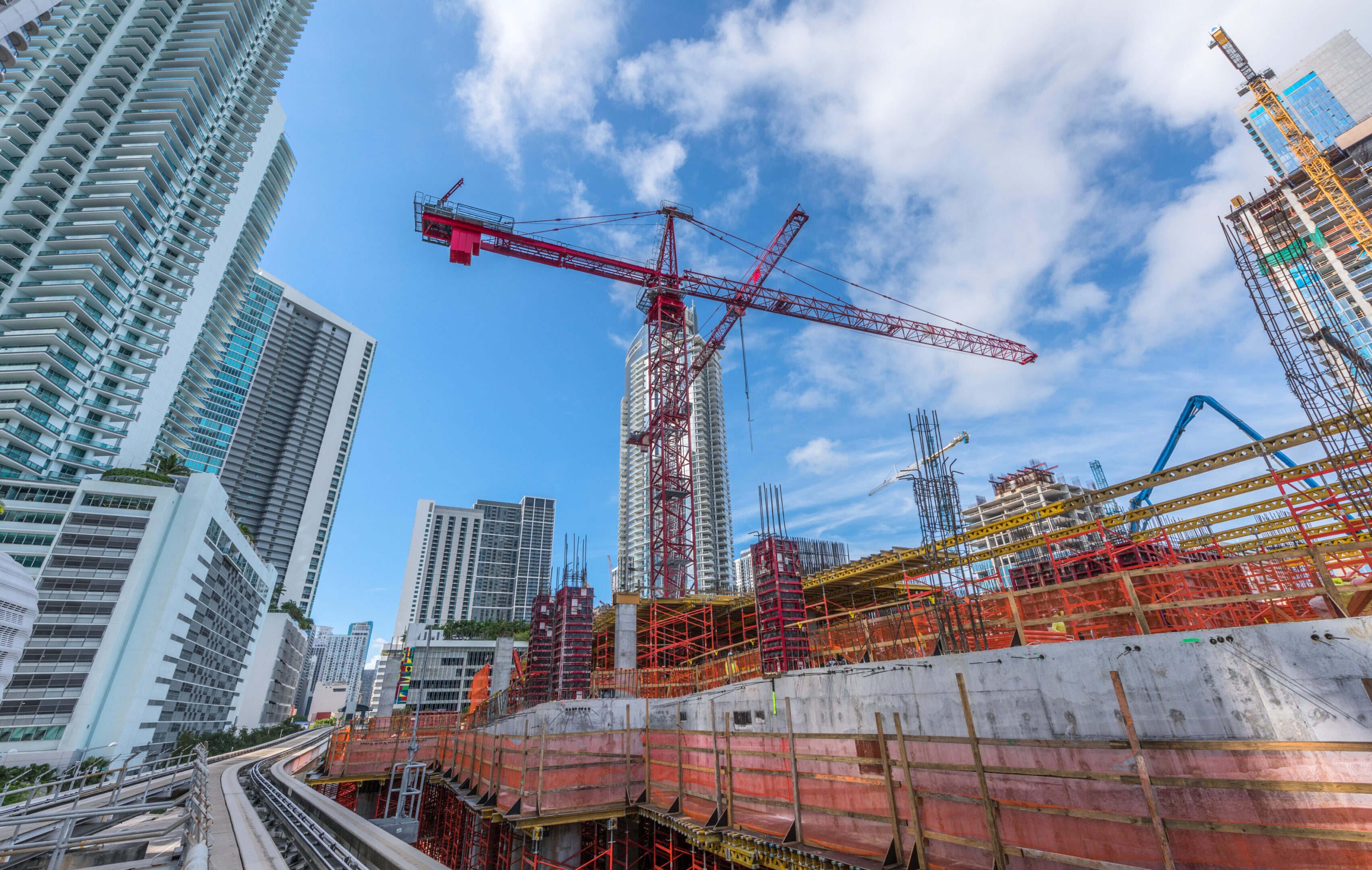 Skyscraper construction with cranes and blue sky.