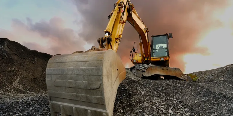 Excavator on rocky terrain at sunset